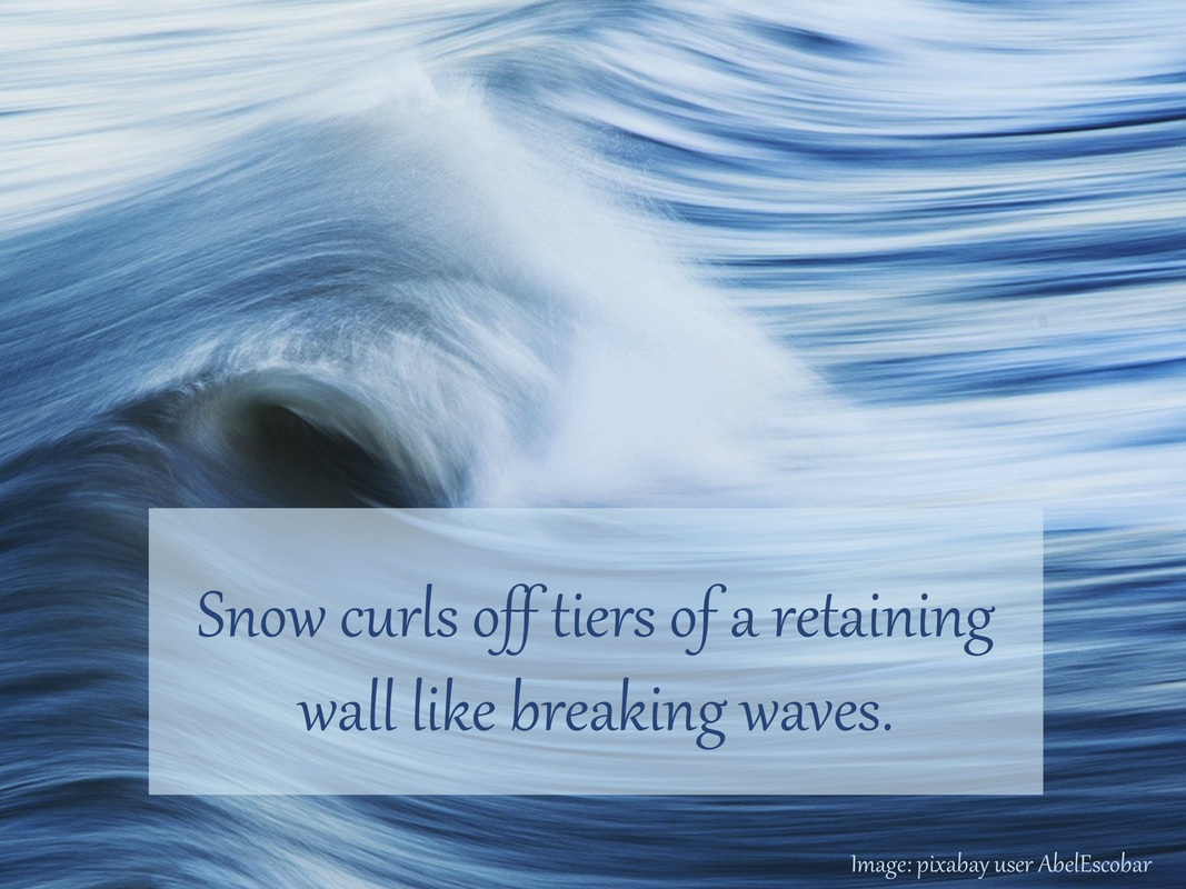 Snow curls off tiers of a retaining wall like breaking waves.